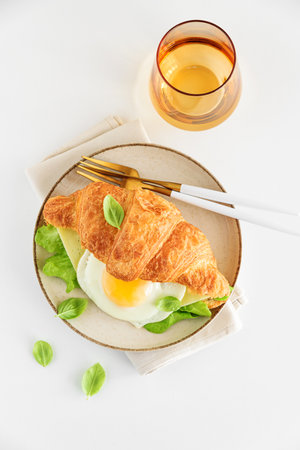 Croissant toast with lettuce, cheese and fried egg on white table. Top viewの写真素材