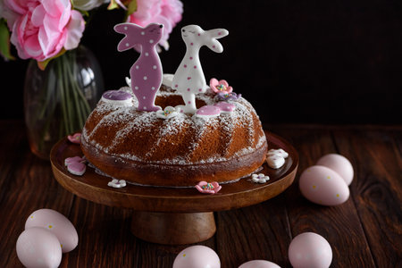 Traditional easter cakes with icing decorated with gingerbread cookies in shape of rabbits on dark...