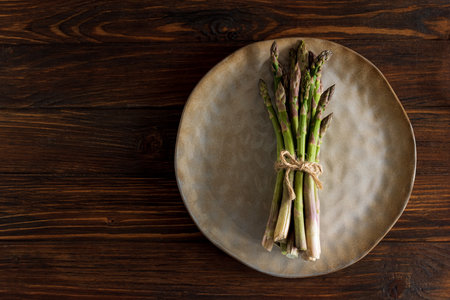 Asparagus tied bundle on brown plate on rustic table. Top viewの写真素材