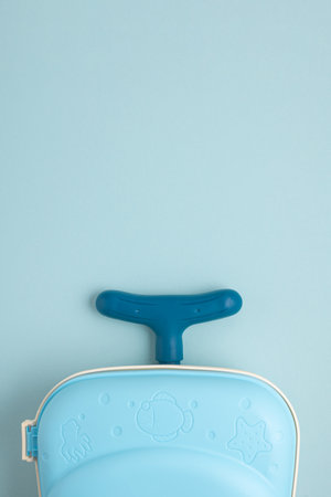 Colorful and playful summer kids beach suitcase on blue background. Top view. Copy spaceの写真素材