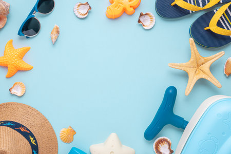 Colorful and playful summer setup featuring kids beach suitcase, molds, straw hat, and sunglasses on blue background. Top view. Copy spaceの写真素材