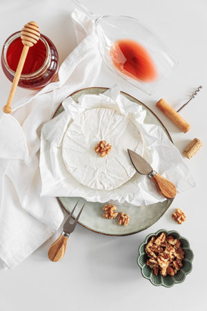 Fresh brie cheese with walnuts and honey, served with wine on white table. Top viewの写真素材