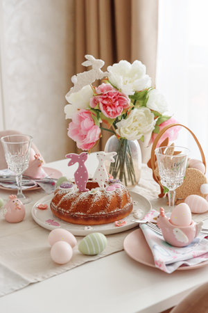 Table setting with traditional easter cakes with icing decorated with gingerbread cookies in shape...