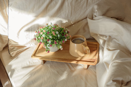 Breakfast in bed with coffee and a potted plant on a wooden tray.