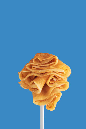 Golden pancakes on a fork against a vibrant blue background.の写真素材