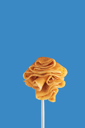 Golden pancakes on a fork against a vibrant blue background.の写真素材