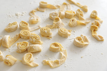Freshly made raw pasta noodles on a white surface.の写真素材