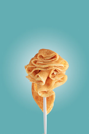 Golden pancakes on a fork against a vibrant blue background.の写真素材