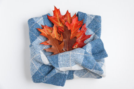 Autumn folded sweater with oak leaves on white background. Top viewの写真素材