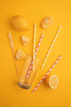 Preparing lemonade. Lemons, straws, and a glass on a vibrant yellow background.の写真素材