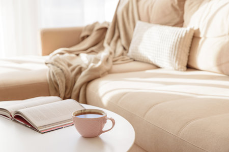 Cozy living room with a book and tea on a beige couch. Soft focusの写真素材