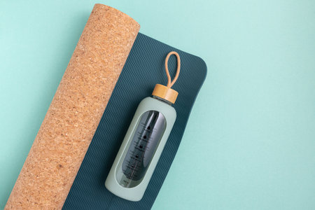 Yoga mat and water bottle on a blue background.の写真素材