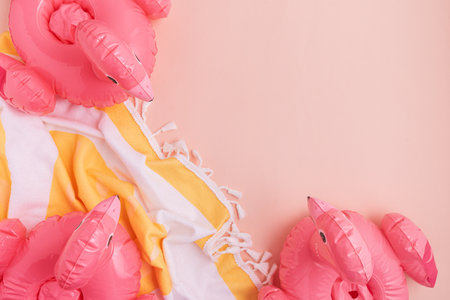 Beach essentials including an inflatable flamingos and towel on a light background.の写真素材