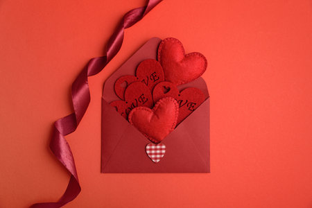 Open red envelope and red felt hearts on red background. Valentines day celebration