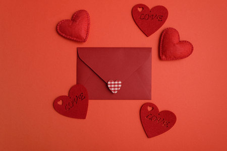 Close red envelope witl love letter and hearts on red background. Valentines day celebration