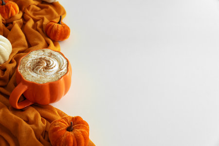 Pumpkin latte with whipped cream and spices, surrounded by autumn decor on white background. Copy spaceの写真素材