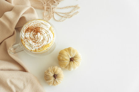 Cozy pumpkin latte with whipped cream and spices, surrounded by autumn decor.の写真素材