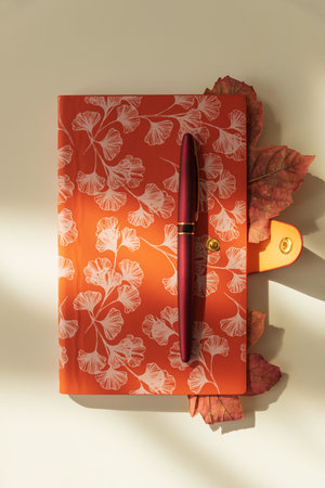 Notebook with Leaves and Pen on Light Background under Sun light