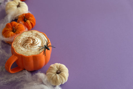 Halloween themed flat lay with a pumpkin latte, decorative pumpkins and spiderwebs on a purple background.の写真素材