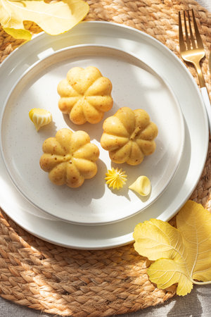 Pumpkin-Shaped Mini Cakes with Cream and Autumn Decor on Woven Placemat