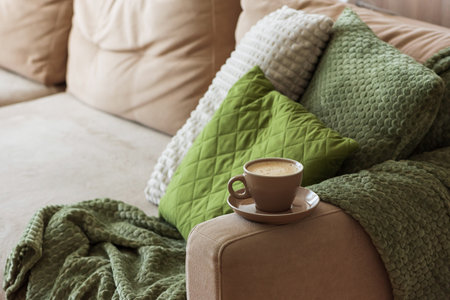Cup of Hot Coffee Stay on Arm of Cozy Couch by Blanket