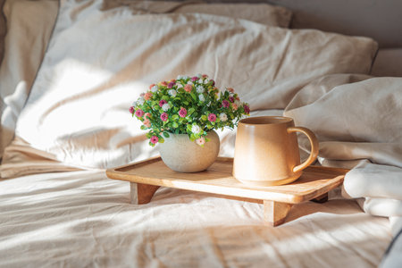 Coffee and Flower Arrangement on Wooden Tray in Cozy Sunlit Interiorの写真素材