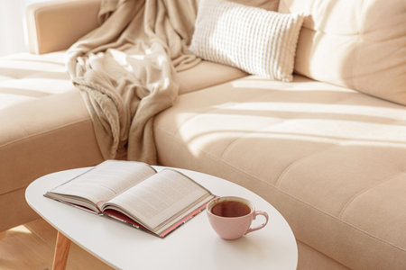 Cozy living room with a book and tea on a beige couch. Soft focusの写真素材