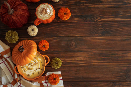 Autumnal lunch with pumpkin soup in a pumpkin-shaped bowl, pumpkin latte, croutons and festive decor on dark wooden table. Top view. Copy spaceの写真素材
