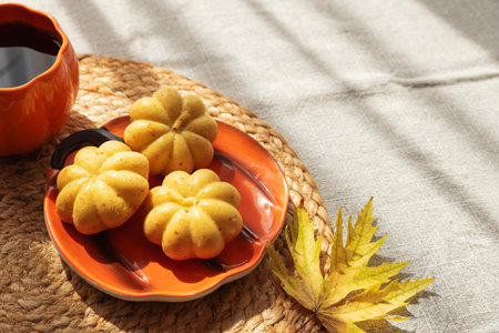 Pumpkin Mug and Mini Cakes with Autumn Leaf on Woven Placematの写真素材