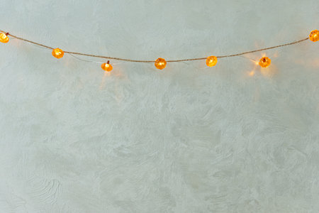 Pumpkin-Shaped String Lights Hanging on Textured Wall for Autumn Decorの写真素材