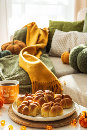 Autumn Table Setting with Pumpkin-Shaped buns with Cinnamon, Apples, Pumpkins, and Cozy Decorの写真素材