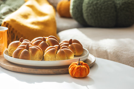 Autumn Table Setting with Pumpkin-Shaped buns with Cinnamon, Apples, Pumpkins, and Cozy Decorの写真素材