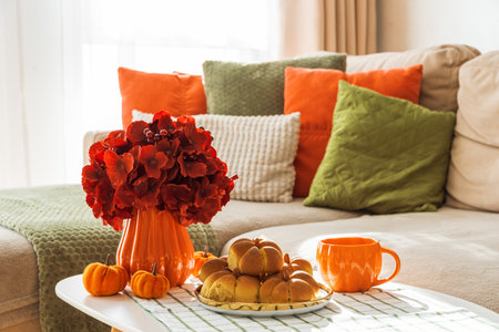 Autumn Living Room with Sofa, Pillows and Pumpkin Cinnamon Buns on Coffee Tableの写真素材