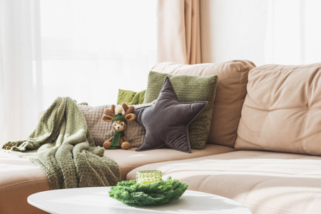 Cozy Living Room with Crocheted Reindeer Toy on Sofa and Christmas Holiday Candle Decor on Tableの写真素材