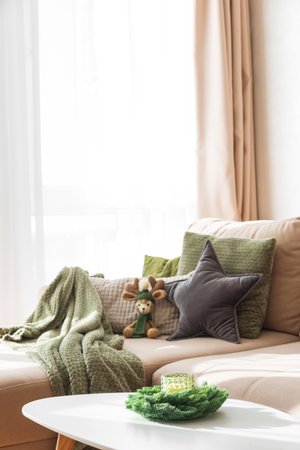 Cozy Living Room with Crocheted Reindeer Toy on Sofa and Christmas Holiday Candle Decor on Tableの写真素材