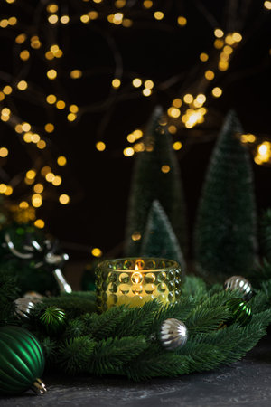 Lit Candle in Green Glass Holder with Pine Wreath and Christmas Ornamentsの写真素材