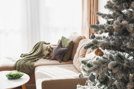 Cozy Living Room with Crocheted Reindeer Toy on Sofa and Christmas Holiday Candle Decor on Tableの写真素材