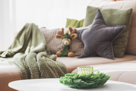 Cozy Living Room with Crocheted Reindeer Toy on Sofa and Christmas Holiday Candle Decor on Tableの写真素材