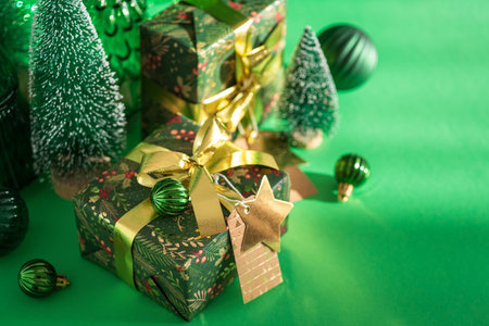 Christmas Gifts with Mini Trees and Green-Gold Ornaments on Festive Backgroundの写真素材