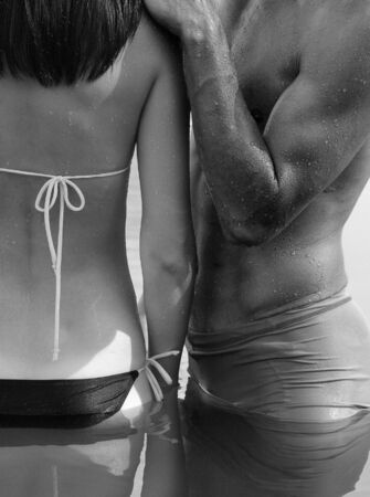 A man embraces a woman standing in the water. Black and white photoの写真素材