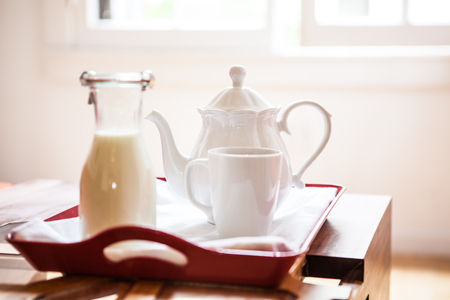 Breakfast tray on a table with milk bottle and teapotの写真素材