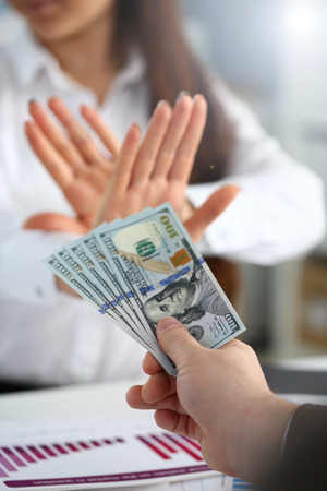 Male arm pay bunch of hundred dollars bills to office clerk closeup. Bribery accept backhander banknote venality laundering back scheme offshore company is kickback collusion lobby gift compensationの写真素材