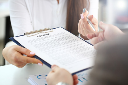 Female arm offer contract form on clipboard pad and silver pen to sign closeup. Strike bargain for profit white collar motivation union decision corporate executive sale insurance agent conceptの写真素材