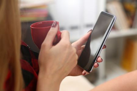 young blond pretty woman drinking coffe and look at laptop in morning sit on sofaの写真素材