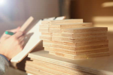 Wooden bars lying in a row closeup with manual worker in background. DIY job, inspiration, improvement, fix shop, powersaw bench, joinery startup, workplace idea, career, ruler, industrial educationの写真素材