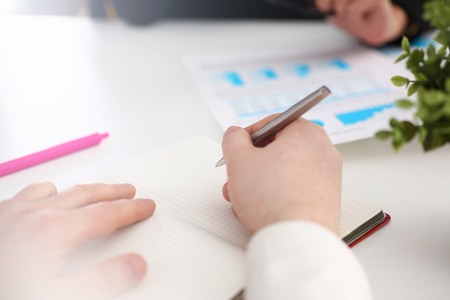 Group of people hold silver pen ready to make note in clipboard pad sheet closeup. Training course university practice homework school or college exercise secretary table management conceptの写真素材