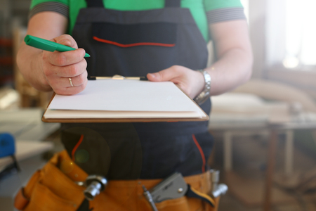 Arms of worker offer clipboard with green pen closeup. Manual job DIY inspiration improvement fix shop graphic joinery startup workplace idea designer career wooden bar rulerの写真素材