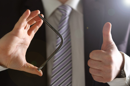 Man in suit and tie bend nail with arms closeup no limit energy easy problem solve issue superman help pressure conceptの写真素材