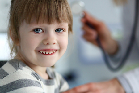Smiling cute little patient interacting with female doctor portraitの写真素材