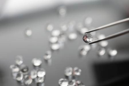 The jeweler holds a diamond in tweezersの写真素材